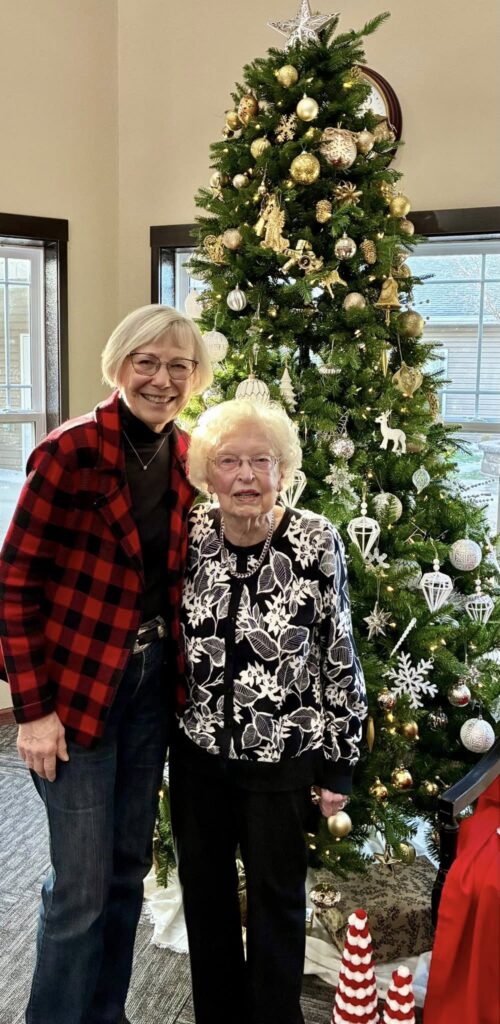 Elderly woman and daughter next to Christmas Tree.